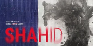 Official poster for Shahid (Berlinale Forum 74): the red spray-painted title “SHAHID” spans the center; at the bottom a woman in a yellow beanie and red coat walks as a robed chorus follows; at right a large gray ink-wash silhouette made of faces looms; festival logo and credits frame the design.
