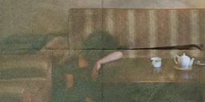 Official poster: grainy, double-exposed room—figure slumped on a sofa with teapot and cup; title “The Photographer, His Lover, His Sister and Her Lover” at left, credits below